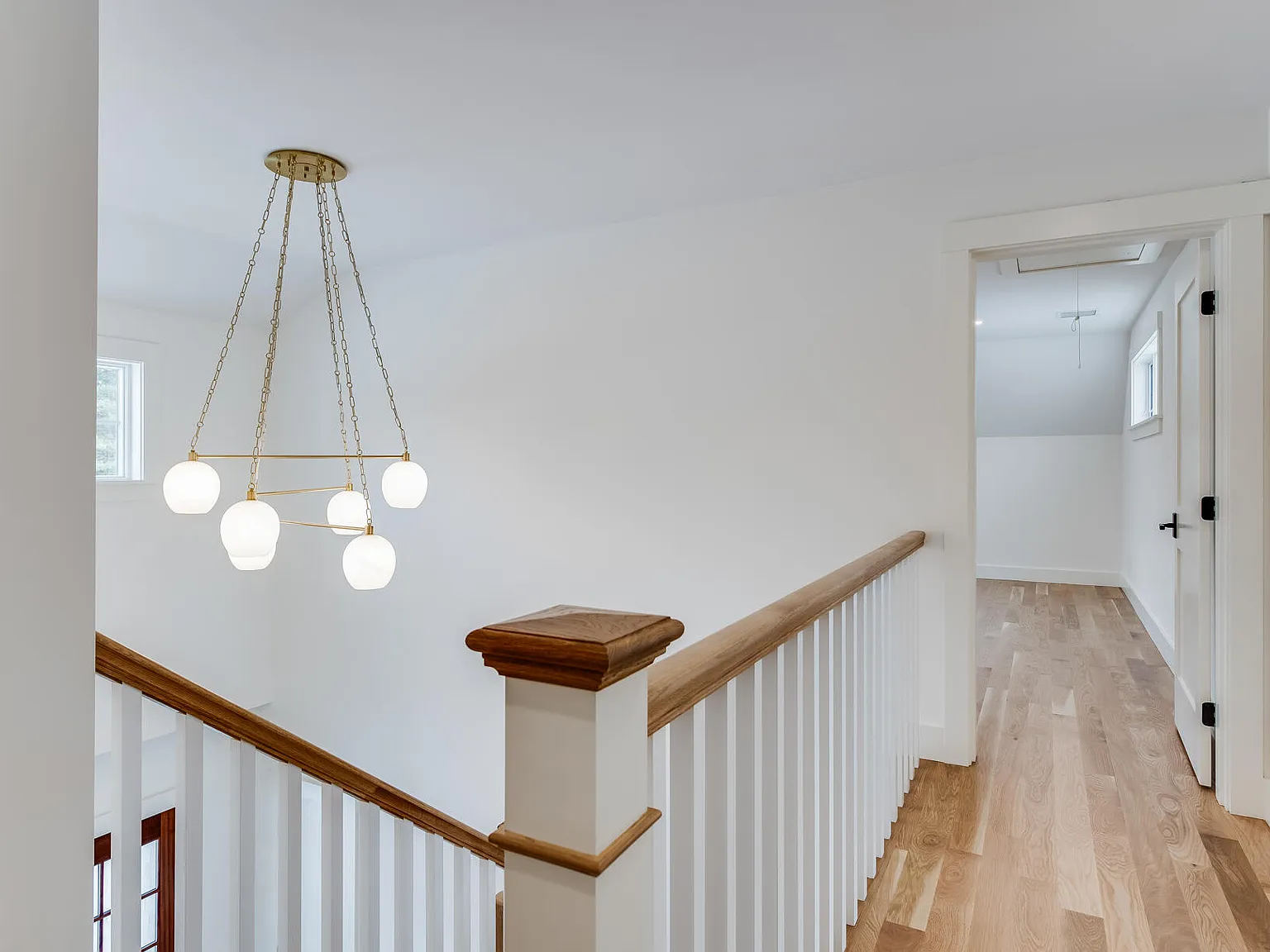 Upper hall — brass globe chandelier, oak railing, white oak hardwood floors