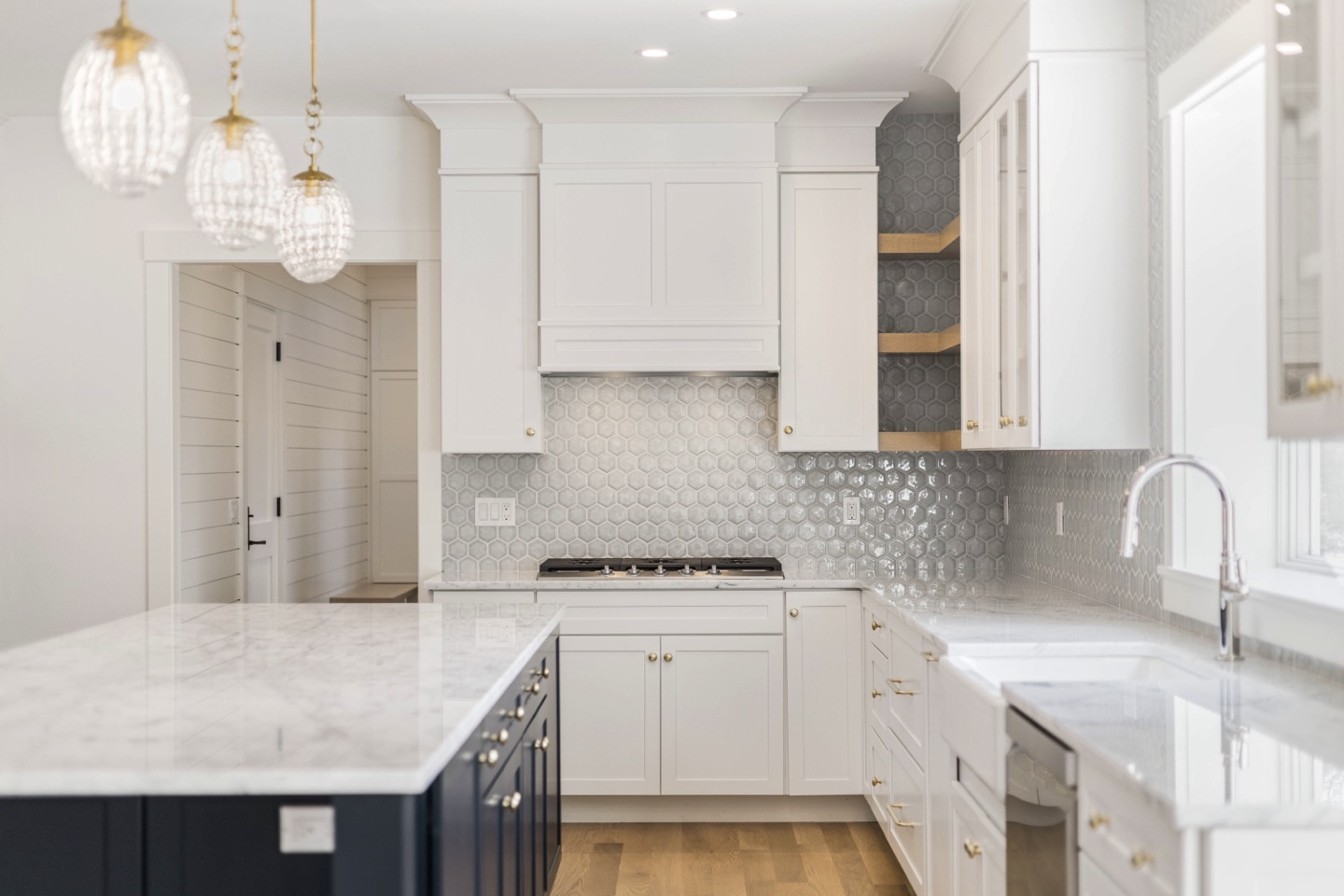 Chef's kitchen — custom range hood, hex tile backsplash, gas cooktop, brass hardware, farmhouse sink